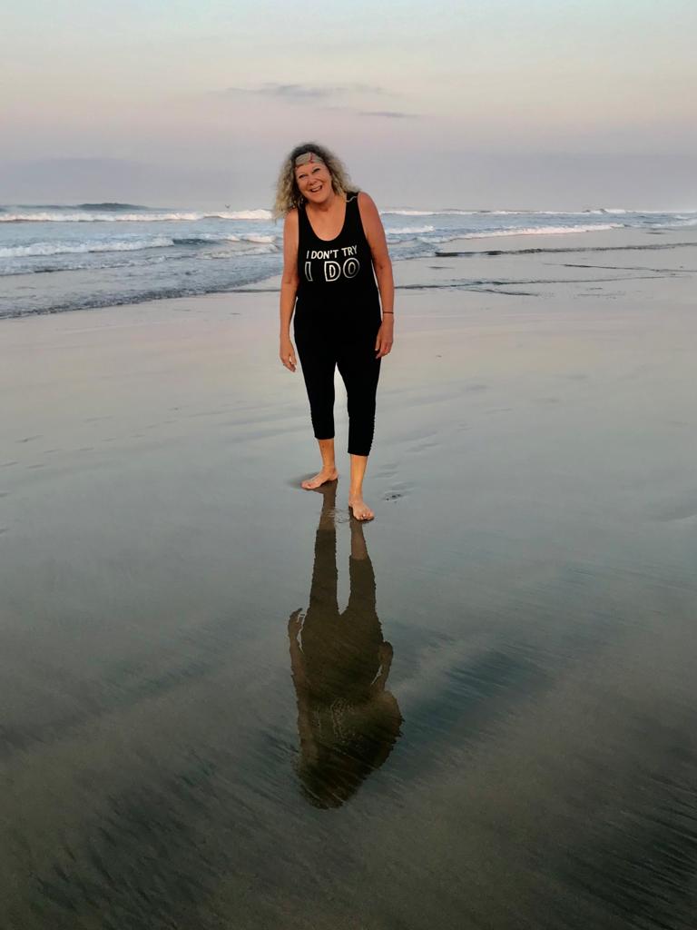 Happy woman on beach, reflection in sand.